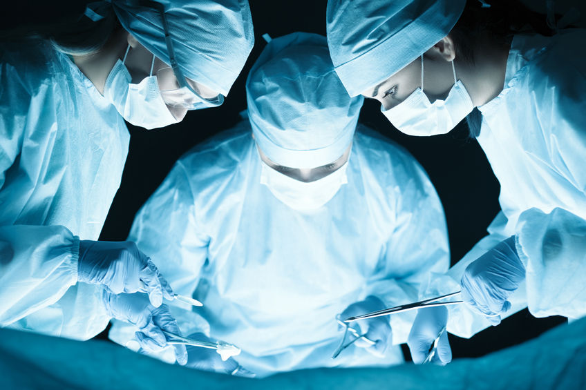 41331167 - medical team performing operation. group of surgeon at work in operating theatre tonned in blue